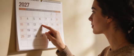 woman looks at wall calendar
